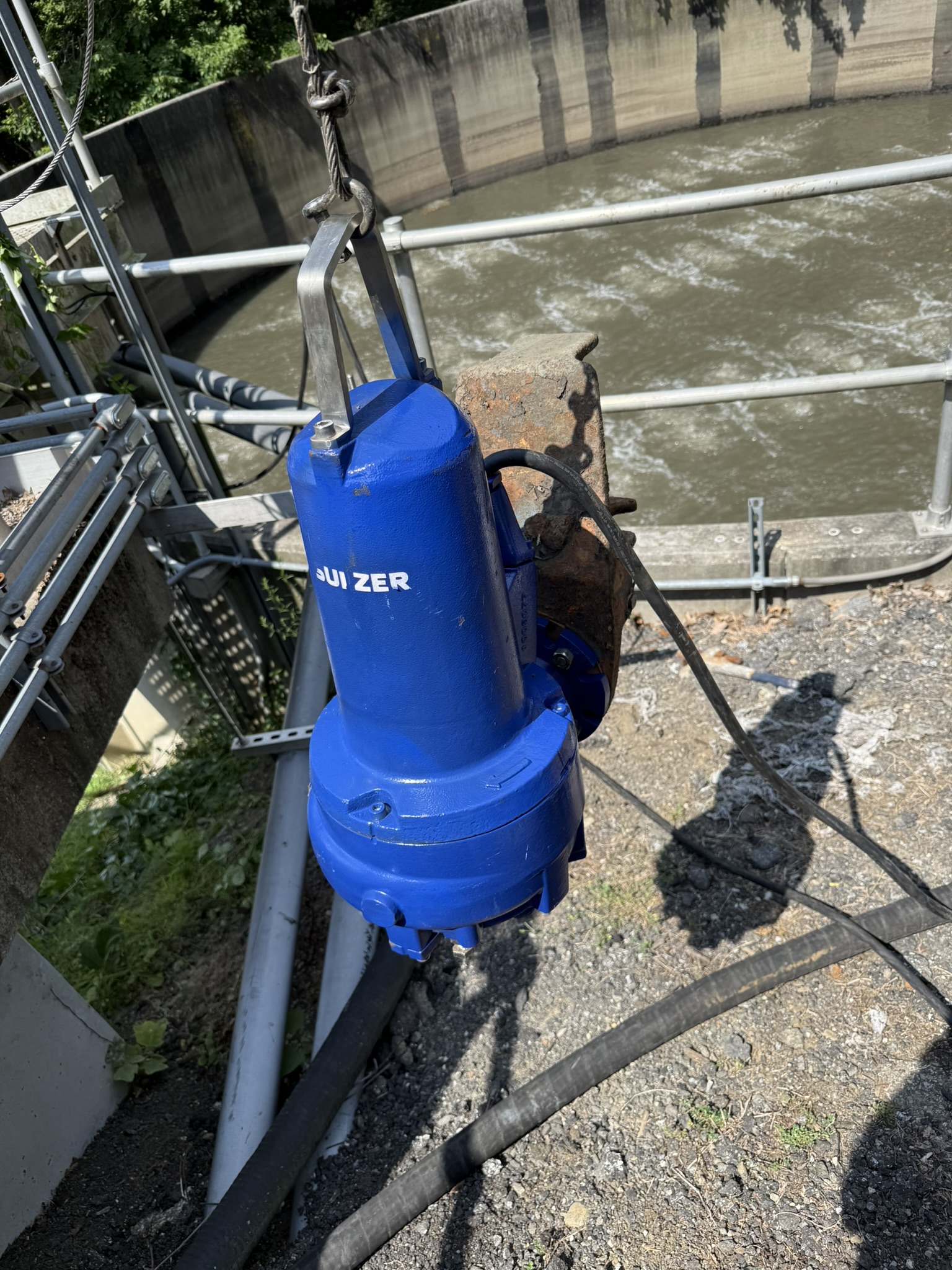Blue submersible pump suspended beside a treatment basin